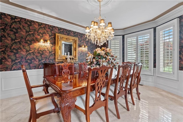 dining room featuring wallpapered walls, crown molding, a decorative wall, wainscoting, and a chandelier