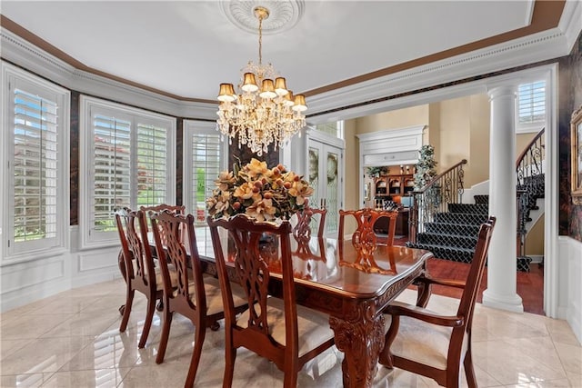 dining area with stairs, a decorative wall, decorative columns, ornamental molding, and an inviting chandelier