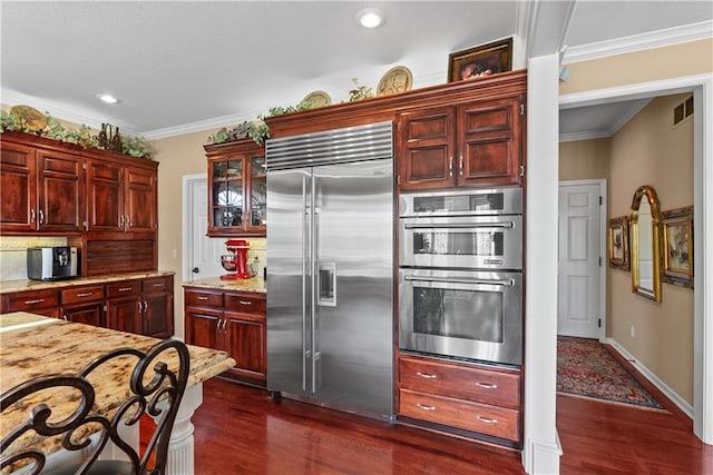 kitchen with reddish brown cabinets, stainless steel appliances, and dark wood-style flooring