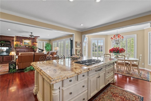 kitchen featuring cream cabinets, dark wood-type flooring, decorative light fixtures, stainless steel gas stovetop, and light stone counters