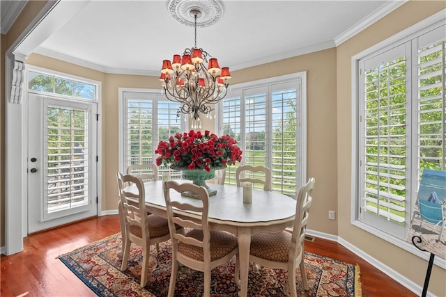 dining space featuring an inviting chandelier, wood finished floors, baseboards, and crown molding