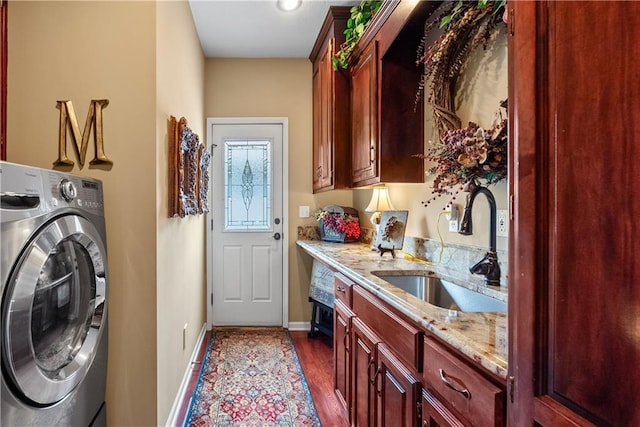 clothes washing area featuring a sink, laundry area, dark wood-type flooring, baseboards, and washer / dryer