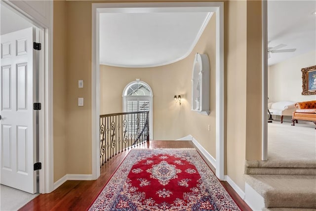hall featuring crown molding, baseboards, an upstairs landing, and dark wood finished floors