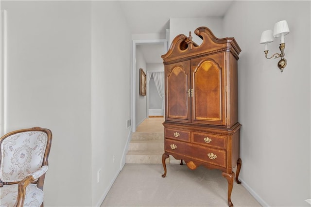 hallway with baseboards, light carpet, and visible vents