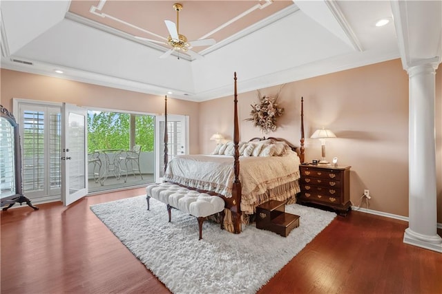 bedroom featuring wood finished floors, ornate columns, baseboards, a tray ceiling, and access to outside