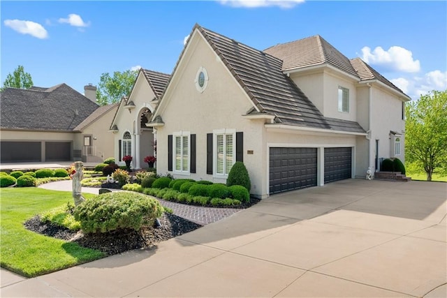 view of front of house with a tile roof, concrete driveway, a garage, and stucco siding