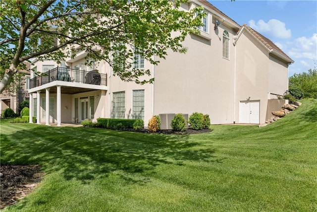 back of house with stucco siding and a lawn