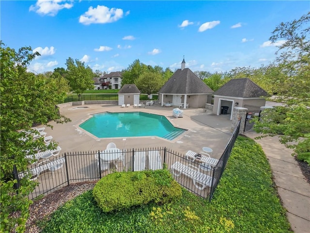 pool featuring a patio area, fence, and an outdoor structure