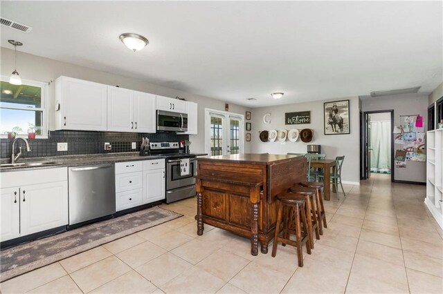 7934 SW James Lee Rd, Polo, MO 64671 - kitchen with stainless steel appliances, dark countertops, tasteful backsplash, white cabinets, and light tile patterned flooring
