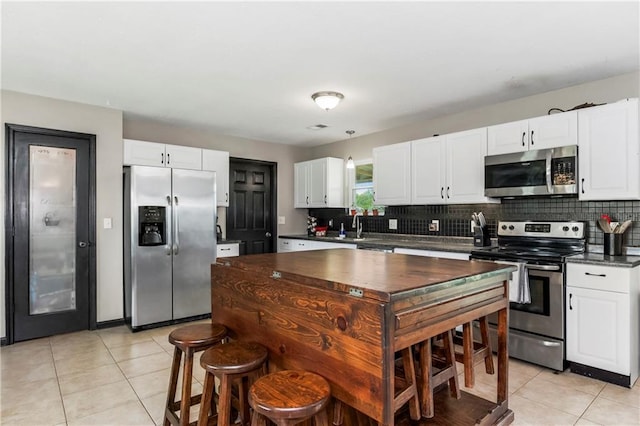 7934 SW James Lee Rd, Polo, MO 64671 - kitchen with stainless steel appliances, dark countertops, light tile patterned flooring, backsplash, and white cabinetry