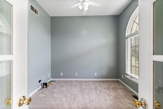 carpeted empty room with a ceiling fan, baseboards, and visible vents