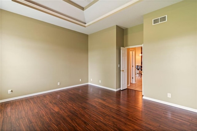 unfurnished room featuring visible vents, baseboards, wood finished floors, and a tray ceiling