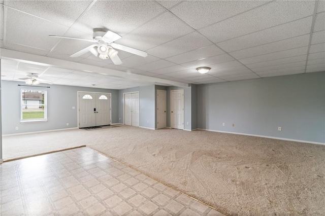 interior space with baseboards, carpet flooring, a ceiling fan, and a drop ceiling