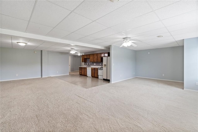 unfurnished living room featuring a ceiling fan, baseboards, and light colored carpet
