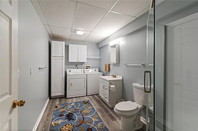 bathroom with vanity, wood finished floors, toilet, a drop ceiling, and independent washer and dryer