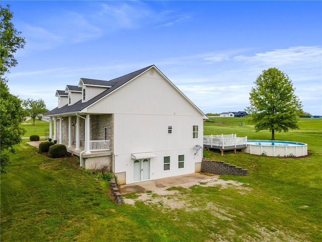 rear view of property featuring a lawn and an outdoor pool