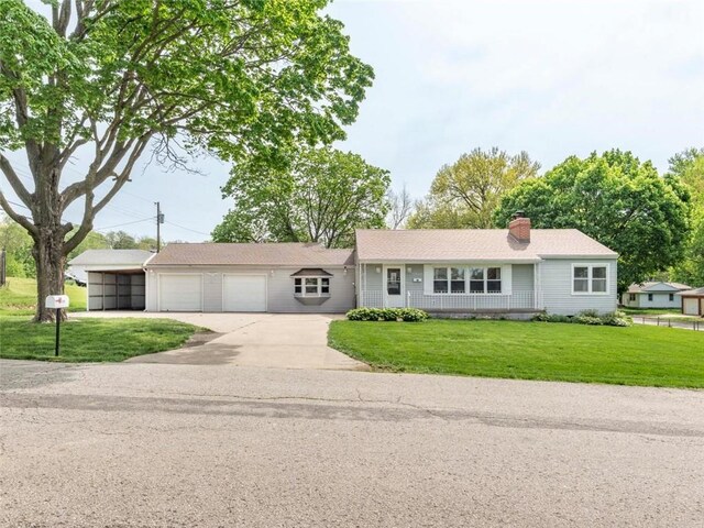 ranch-style home featuring a chimney, a garage, a front yard, and concrete driveway