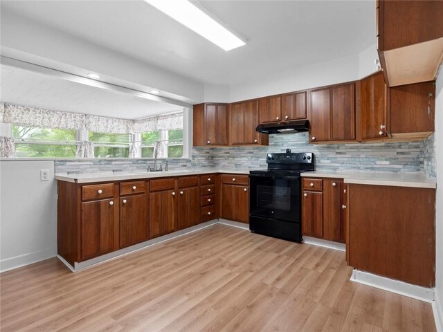 kitchen featuring under cabinet range hood, light countertops, light wood-style floors, and black range with electric stovetop