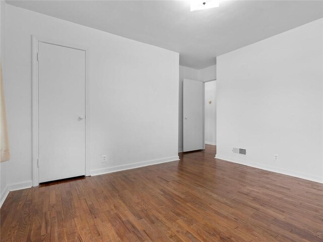 unfurnished room with baseboards, visible vents, and wood finished floors