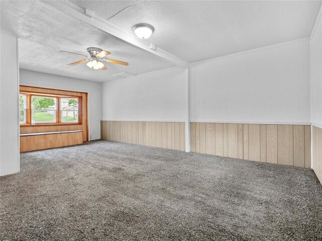 unfurnished room featuring a ceiling fan, carpet, a textured ceiling, and wooden walls