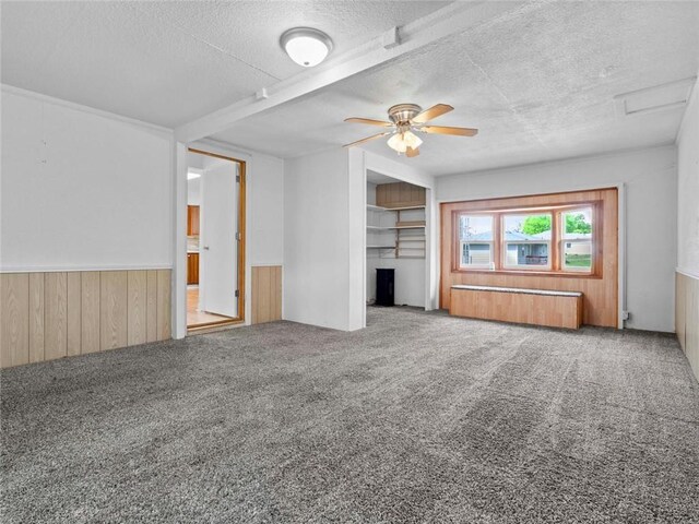 unfurnished living room featuring carpet flooring, a textured ceiling, wood walls, and radiator heating unit
