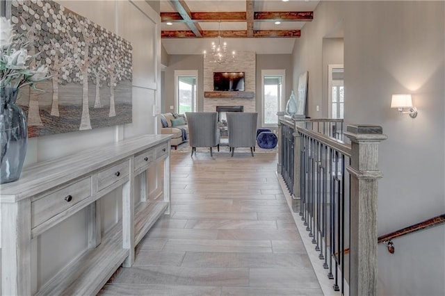 corridor with light wood-type flooring, coffered ceiling, a healthy amount of sunlight, and beamed ceiling