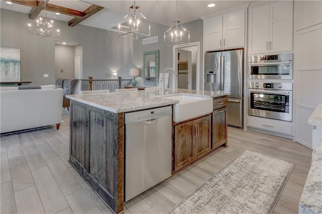 kitchen featuring an inviting chandelier, a sink, stainless steel appliances, open floor plan, and visible vents