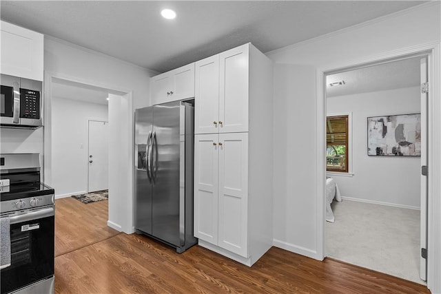 2521 W 47th Ter, Westwood, KS 66205 - kitchen with stainless steel appliances, white cabinets, dark wood-style floors, ornamental molding, and recessed lighting