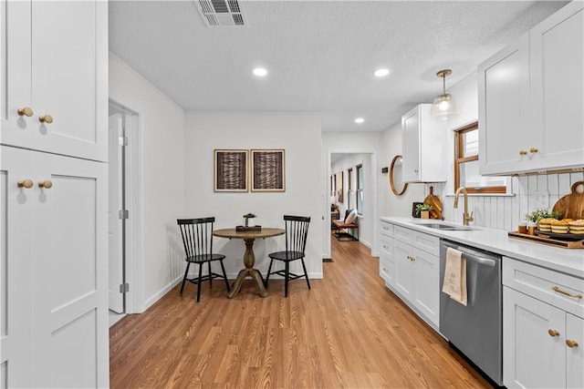 2521 W 47th Ter, Westwood, KS 66205 - kitchen with stainless steel dishwasher, a sink, light wood-type flooring, light countertops, and white cabinetry