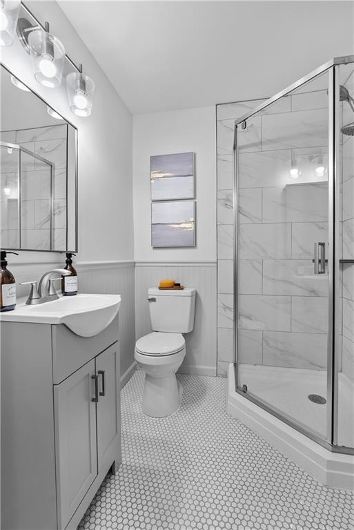 2521 W 47th Ter, Westwood, KS 66205 - bathroom featuring toilet, vanity, a wainscoted wall, a stall shower, and tile patterned flooring