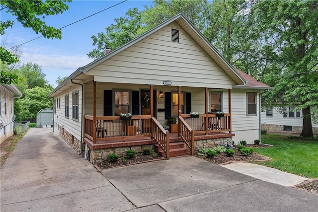 2521 W 47th Ter, Westwood, KS 66205 - view of front of house featuring covered porch, an outbuilding, a chimney, concrete driveway, and a front yard