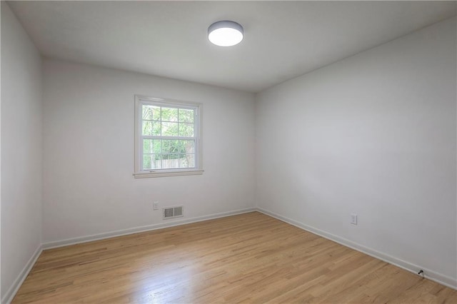 empty room featuring visible vents, baseboards, and light wood-type flooring