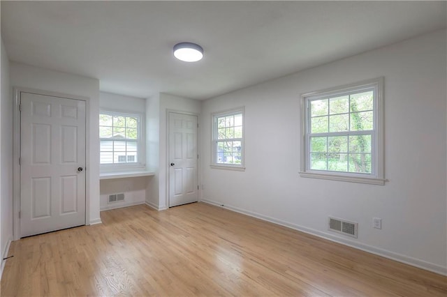 unfurnished bedroom featuring baseboards, multiple windows, and visible vents