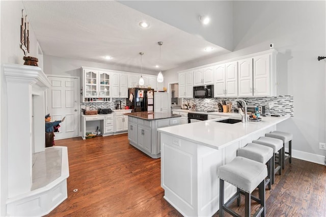 4504 NE 60th Ter, Kansas City, MO 64119 - kitchen with a sink, a breakfast bar area, decorative backsplash, a kitchen island, and black appliances