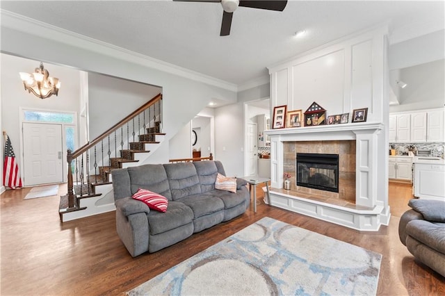 4504 NE 60th Ter, Kansas City, MO 64119 - living area with ceiling fan with notable chandelier, stairs, wood finished floors, a tile fireplace, and ornamental molding