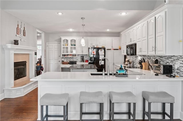 4504 NE 60th Ter, Kansas City, MO 64119 - kitchen with a peninsula, a breakfast bar area, white cabinetry, tasteful backsplash, and black appliances
