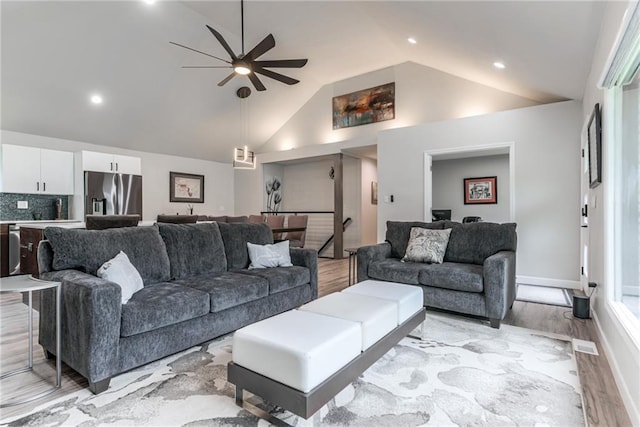 living area featuring ceiling fan, high vaulted ceiling, light wood-style flooring, recessed lighting, and baseboards