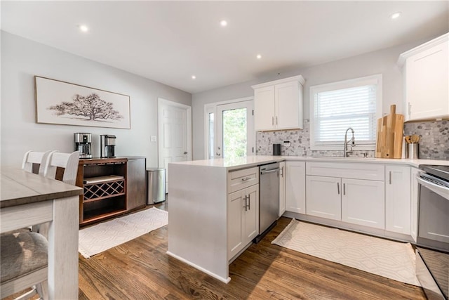 kitchen with a sink, a peninsula, white cabinetry, and appliances with stainless steel finishes
