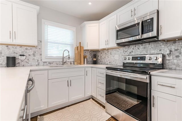 kitchen featuring white cabinets, stainless steel appliances, decorative backsplash, and a sink