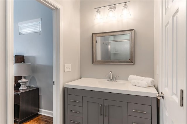 bathroom with vanity, baseboards, walk in shower, and wood finished floors
