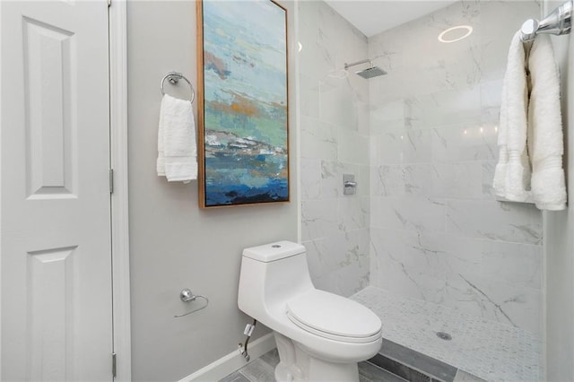bathroom with baseboards, a shower stall, and toilet