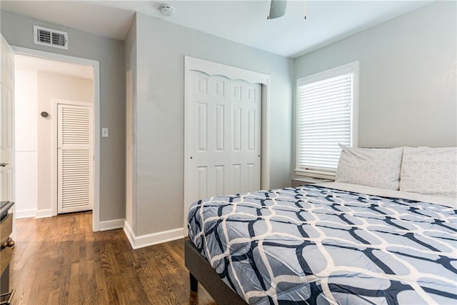bedroom with dark wood finished floors, a ceiling fan, baseboards, visible vents, and a closet