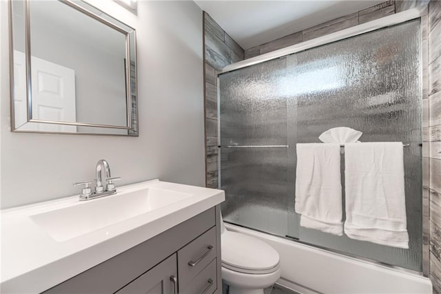 full bathroom featuring vanity, bath / shower combo with glass door, and toilet