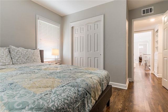 bedroom with baseboards, a closet, wood finished floors, and visible vents