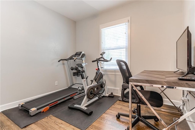 workout room featuring baseboards, wood finished floors, and visible vents