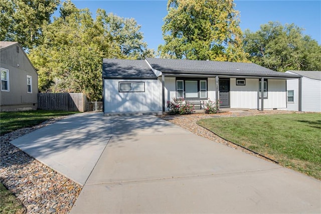 single story home with a porch, roof with shingles, a front yard, fence, and concrete driveway