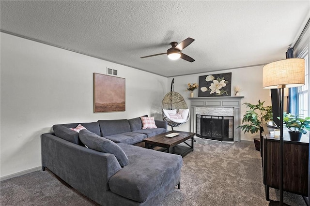 carpeted living area featuring ceiling fan, a brick fireplace, a textured ceiling, baseboards, and visible vents