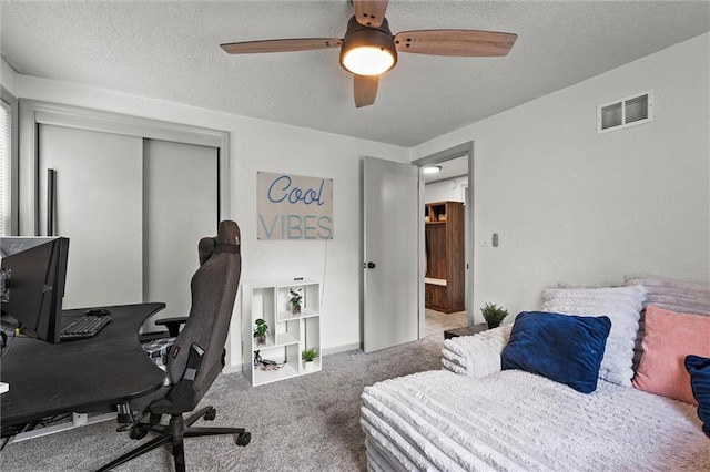 bedroom with ceiling fan, a textured ceiling, visible vents, a closet, and carpet