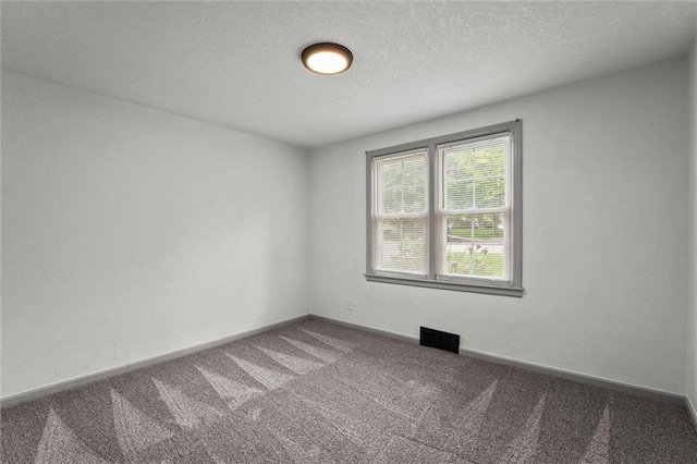 carpeted spare room with a textured ceiling, visible vents, and baseboards