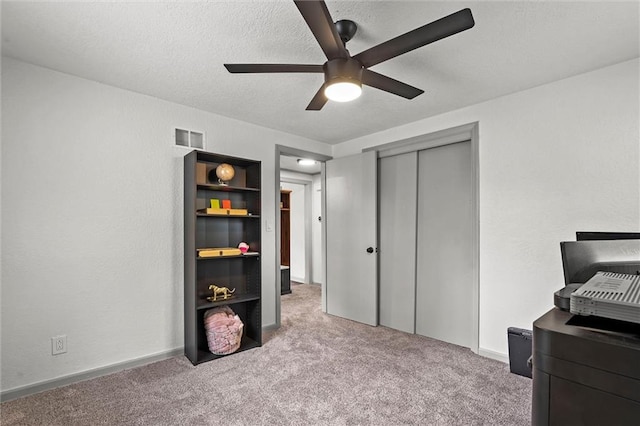 carpeted bedroom with a ceiling fan, a textured ceiling, visible vents, and a closet
